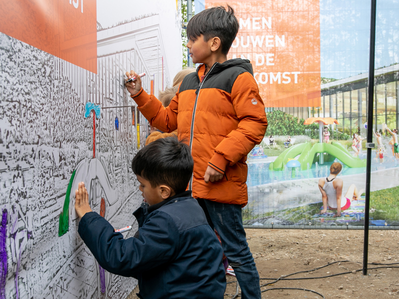 Tijdens de feestelijke viering mogen aanwezige kinderen het bouwhekdoek inkleuren.